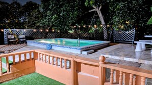 A swimming pool with a tiled edge, surrounded by a fence, and a wooden deck with a railing. - Lush oasis in port of Spain with private pool (Port of Spain)