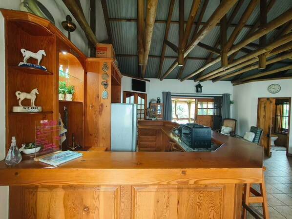 A rustic kitchen with wooden beams, a wooden counter, and a refrigerator.