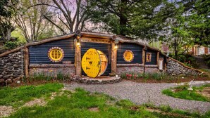 A rustic cabin with a large yellow door, stone walls, and circular windows. - Enchanting and Fantastical Hobbit Home, *Pet Friendly*, Steps from Creeks, Pond, and Waterfall (Salem)