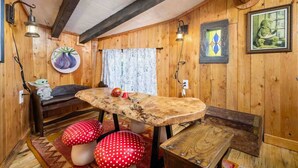 A wooden interior with a round table, benches, and a wall-mounted lamp. - Enchanting and Fantastical Hobbit Home, *Pet Friendly*, Steps from Creeks, Pond, and Waterfall (Salem)