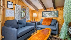 A cozy room with wooden walls, two blue sofas, a small table with a lamp, and a framed picture on the wall. - Enchanting and Fantastical Hobbit Home, *Pet Friendly*, Steps from Creeks, Pond, and Waterfall (Salem)
