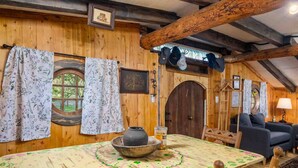 A rustic wooden interior with a dining table, chairs, a sofa, and a large wooden door. - Enchanting and Fantastical Hobbit Home, *Pet Friendly*, Steps from Creeks, Pond, and Waterfall (Salem)