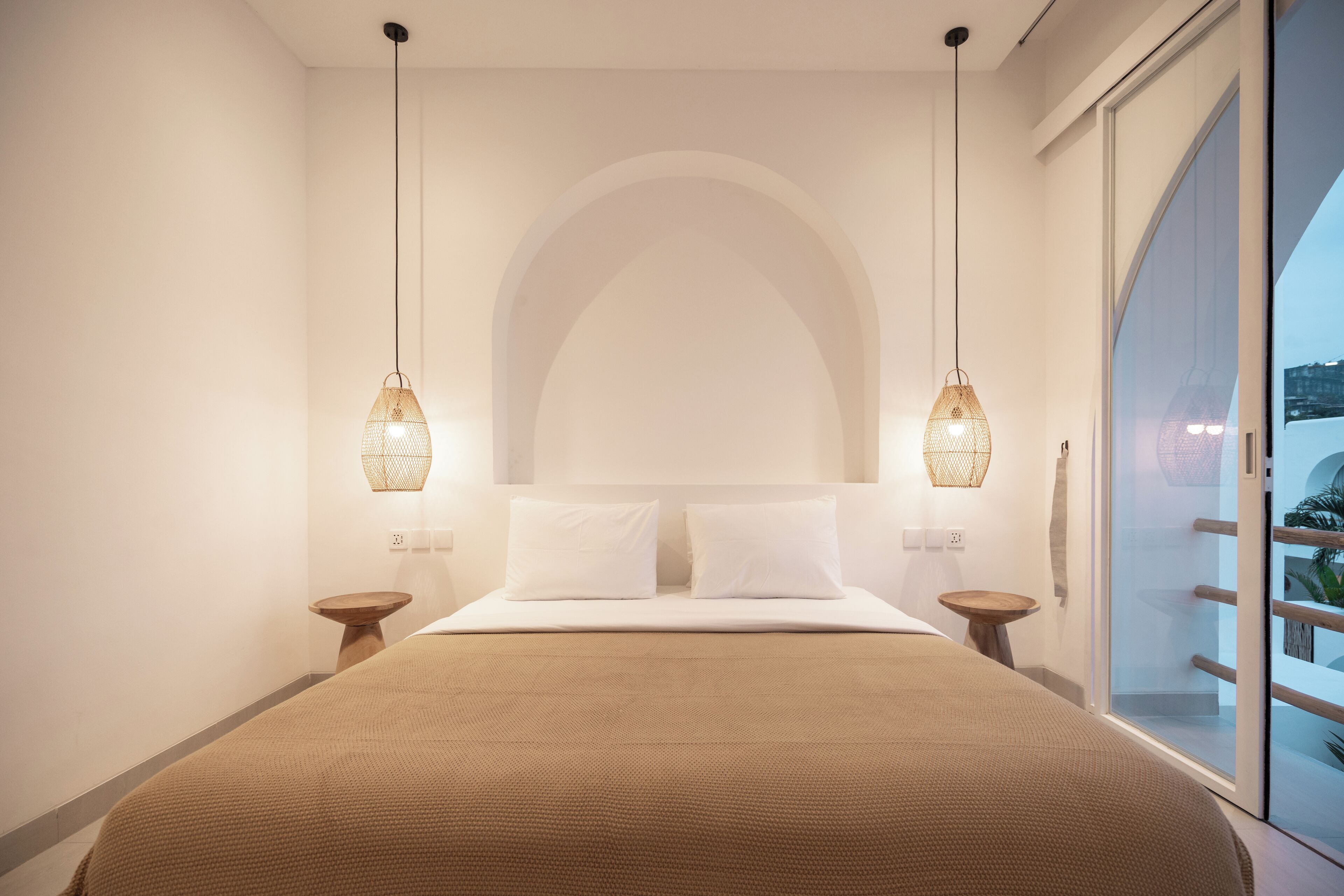 A modern bedroom with a large bed, two bedside tables, and a large window with a view.