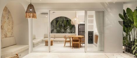 A modern interior with a pool, a dining area with a table and chairs, a sofa, and a hanging light fixture.