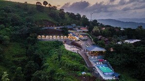 A resort with a swimming pool, a covered walkway, and a series of lights along the path. - The Hosteller Panshet, Lakeview  (Pune)