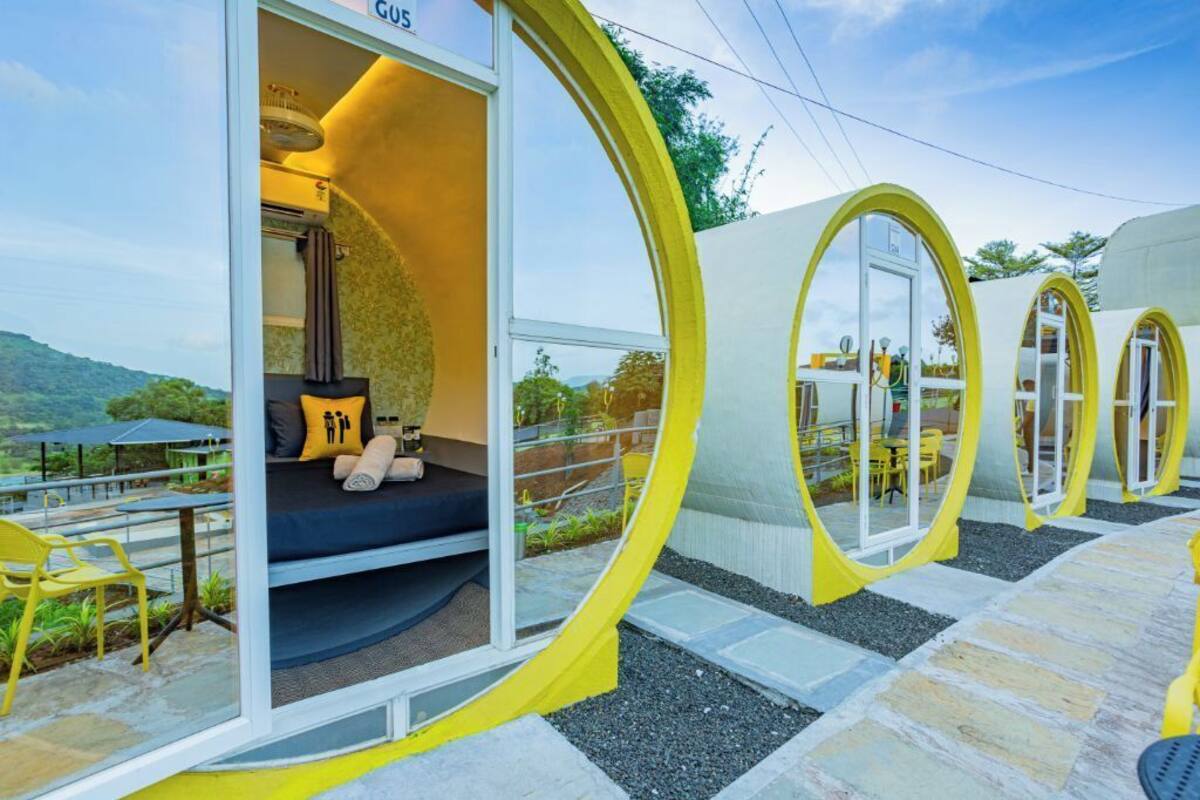 A modern accommodation with circular rooms, each featuring a bed, seating area, and a view of the surrounding landscape.