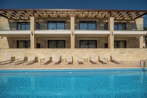 Un hotel con piscina, varios balcones y tumbonas.