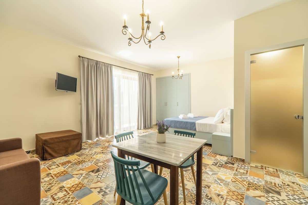 A hotel room with a dining area, a bed, a TV, and a bathroom.