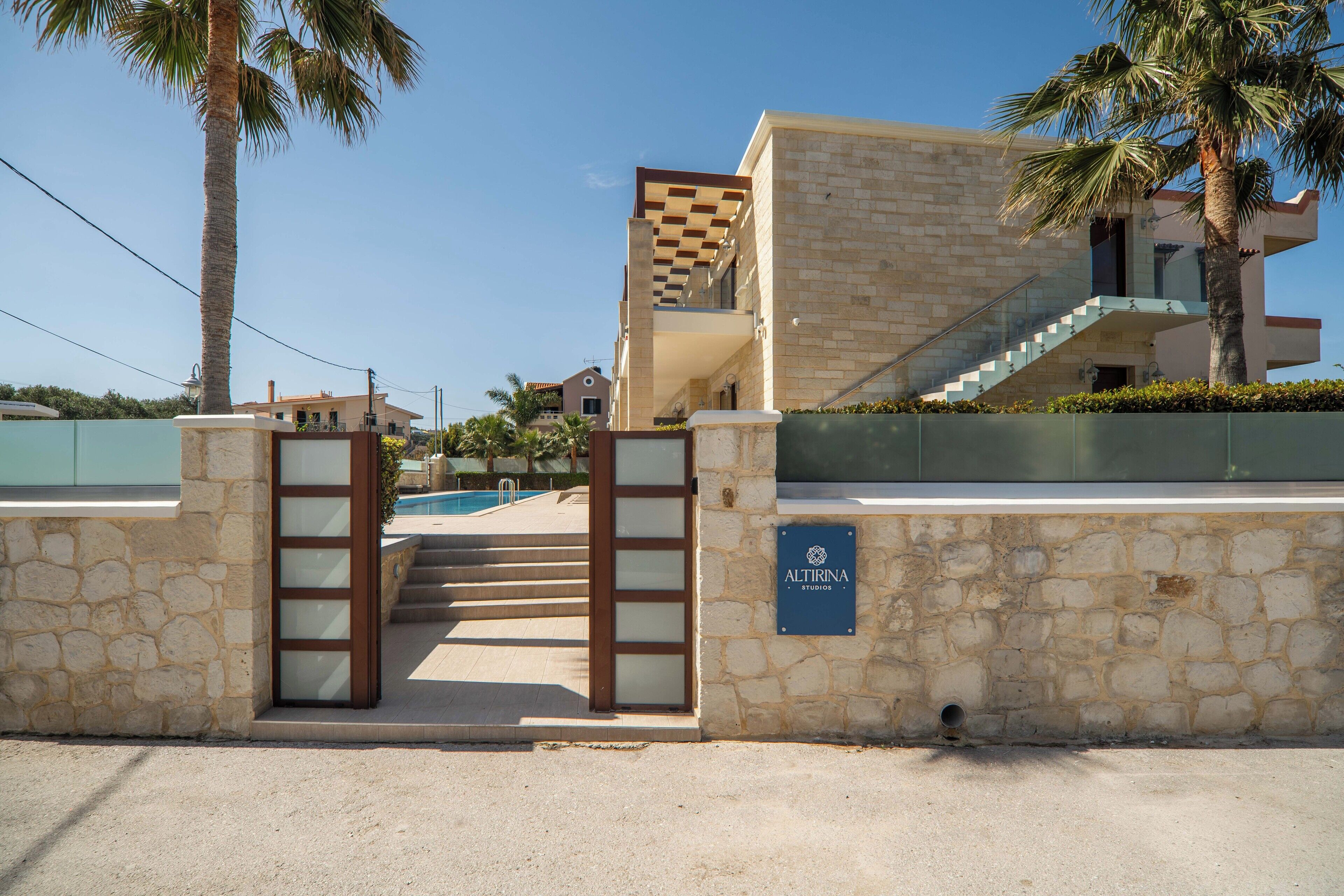 A modern building with a stone facade, a pool, and a staircase leading to a balcony.
