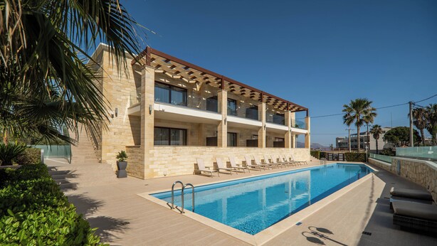 A modern hotel with a pool, multiple balconies, and a clear view of the sea. - Altirina Studios (Almyrida)