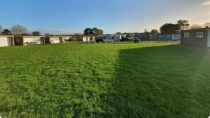 Un champ herbeux avec des mobil-homes et un petit bâtiment en arrière-plan.