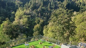 A group of people dancing on a grassy outdoor area with tables and chairs, surrounded by trees and a mountainous backdrop. - Gurugram Resort Mussoorie (Mussoorie)