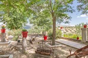 Un giardino con piante in vaso, una struttura metallica rustica e vista su colline lontane.