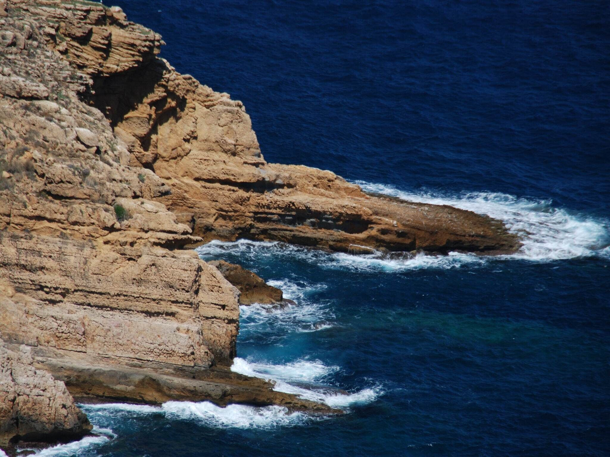 A coastal cliff with waves crashing against it.