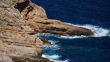 A coastal cliff with waves crashing against it.