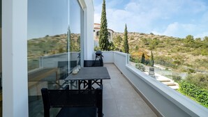 A balcony with a table and chairs, overlooking a hilly landscape with trees and a building in the distance. - Modern Stay near Monte Solana (Pedreguer)