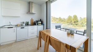 A modern kitchen with white cabinetry, a wooden dining table, and a large window offering a view of trees and hills. - Modern Stay near Monte Solana (Pedreguer)