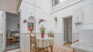 Un pequeño y acogedor comedor con una mesa redonda y sillas, rodeado de paredes blancas y suelo de baldosas.