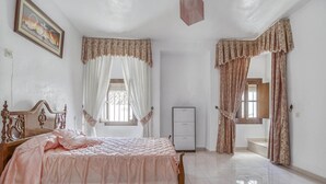 Un dormitorio con cama, armario y ventana con cortinas.