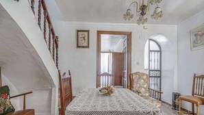 Comedor con mesa lista para cuatro, una escalera y vistas al exterior.