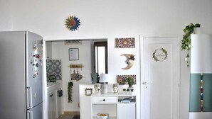 A kitchen with white cabinets, a refrigerator, and various decorative items including a sun decoration, a moon decoration, and a heart-shaped decoration. - Panoramic cottage 100 mt from the main square view Taormina and Calabria (Castelmola)