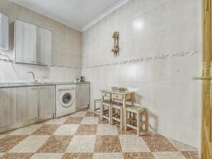 A compact kitchen with a washing machine, a sink, and a small table with chairs.