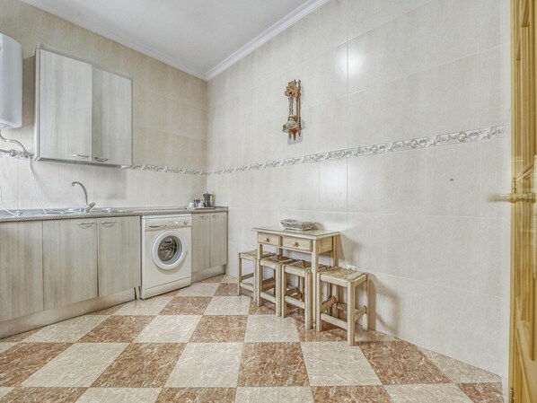 A compact kitchen with a washing machine, a sink, and a small table with chairs.