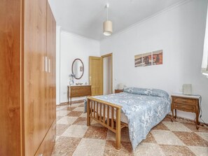 A bedroom with a wooden bed, a dresser, a mirror, and a door.