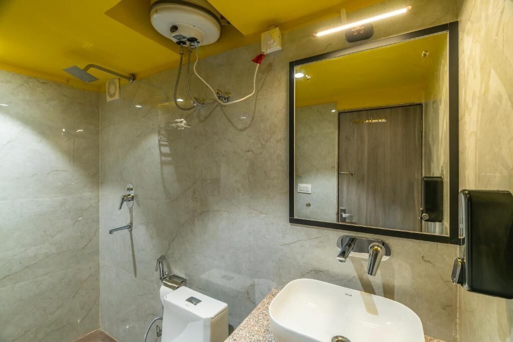 Ein modernes Badezimmer mit Marmorwand, einem großen Spiegel, einem Waschbecken und einer Dusche.