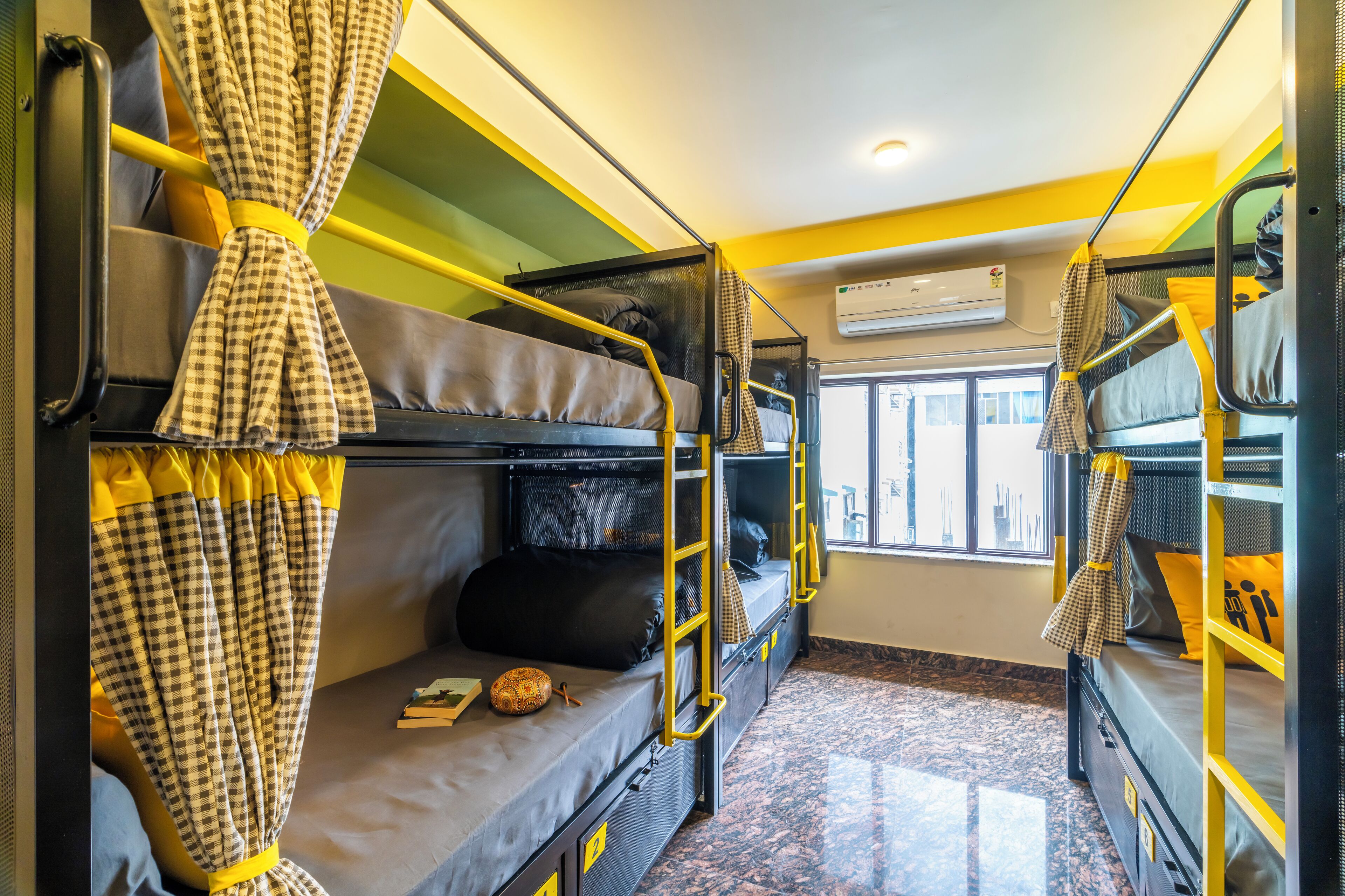 A train compartment with bunk beds, yellow handrails, and a window providing natural light.