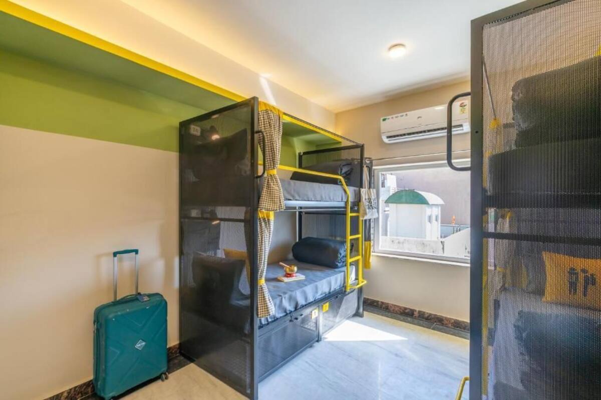 Une petite chambre avec des lits superposés, une valise et une fenêtre donnant sur un beau paysage.