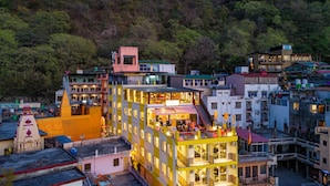A multi-story hotel with balconies and a restaurant on the ground floor. - The Hosteller Rishikesh, Ganges (RISHIKESH)