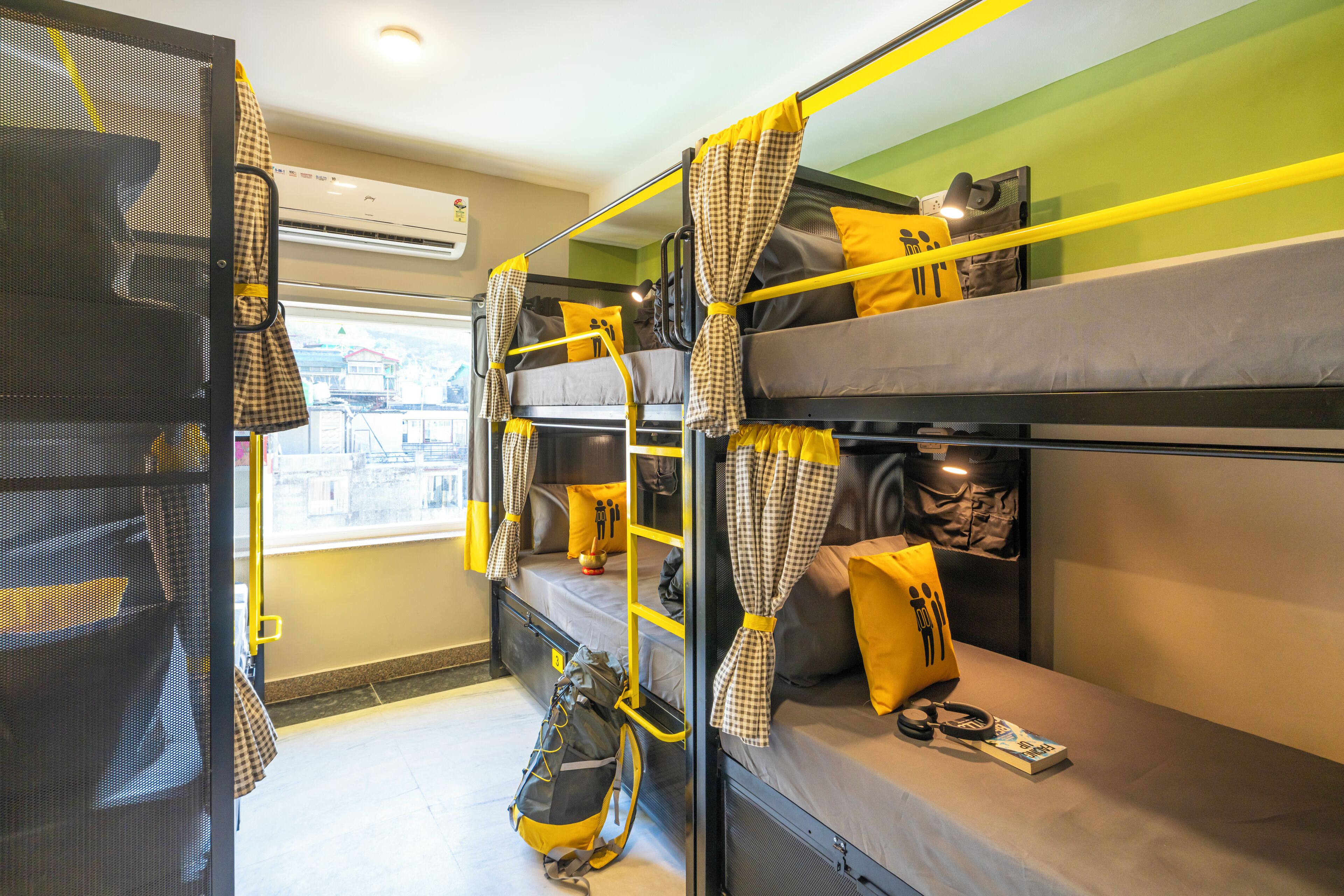 A bunk bed room with yellow curtains, a window, and a bag on the lower bunk.