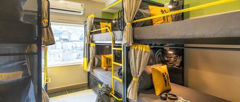 A bunk bed room with yellow curtains, a window, and a bag on the lower bunk.