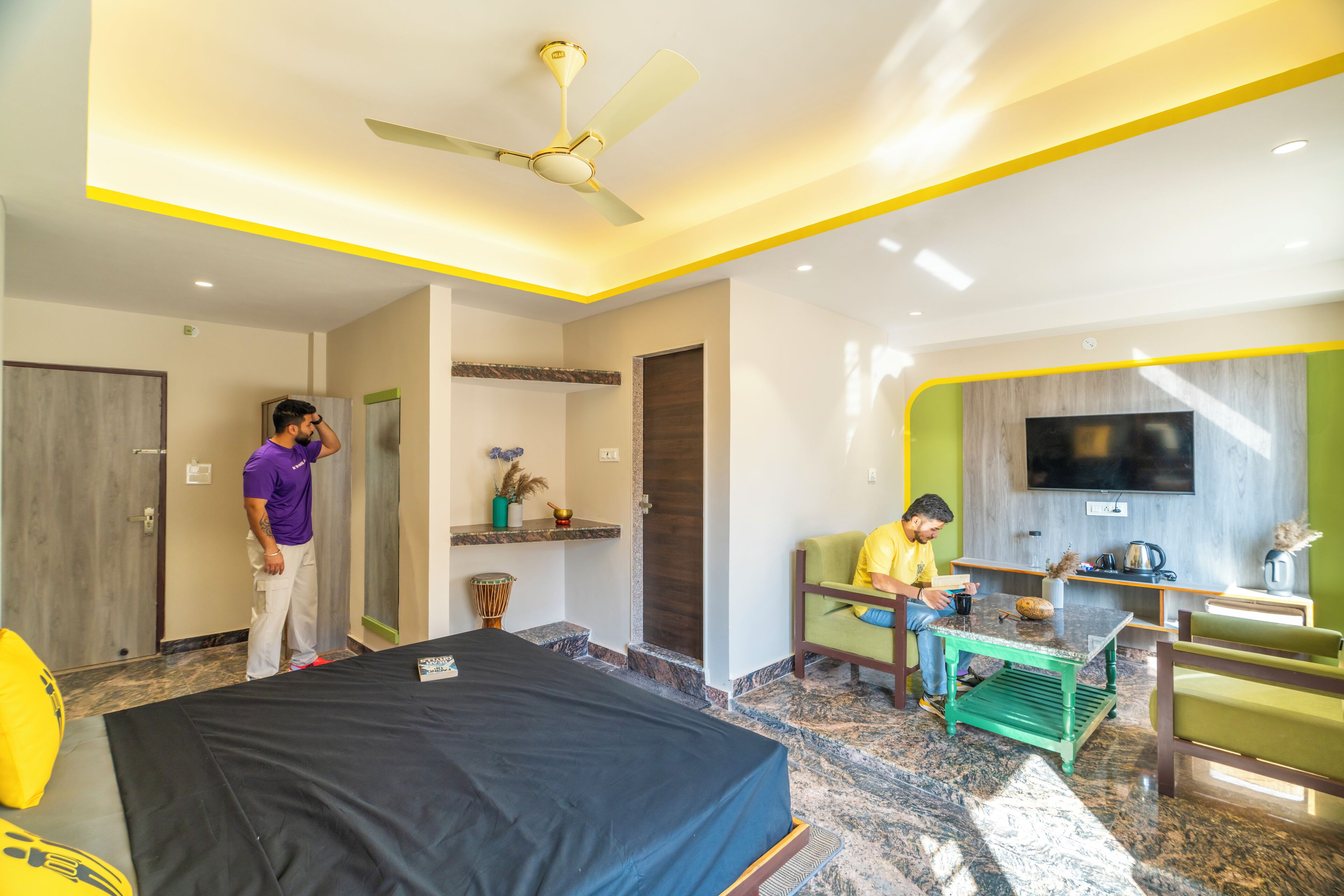 A hotel room with a bed, a desk, a chair, a television, and a ceiling fan.