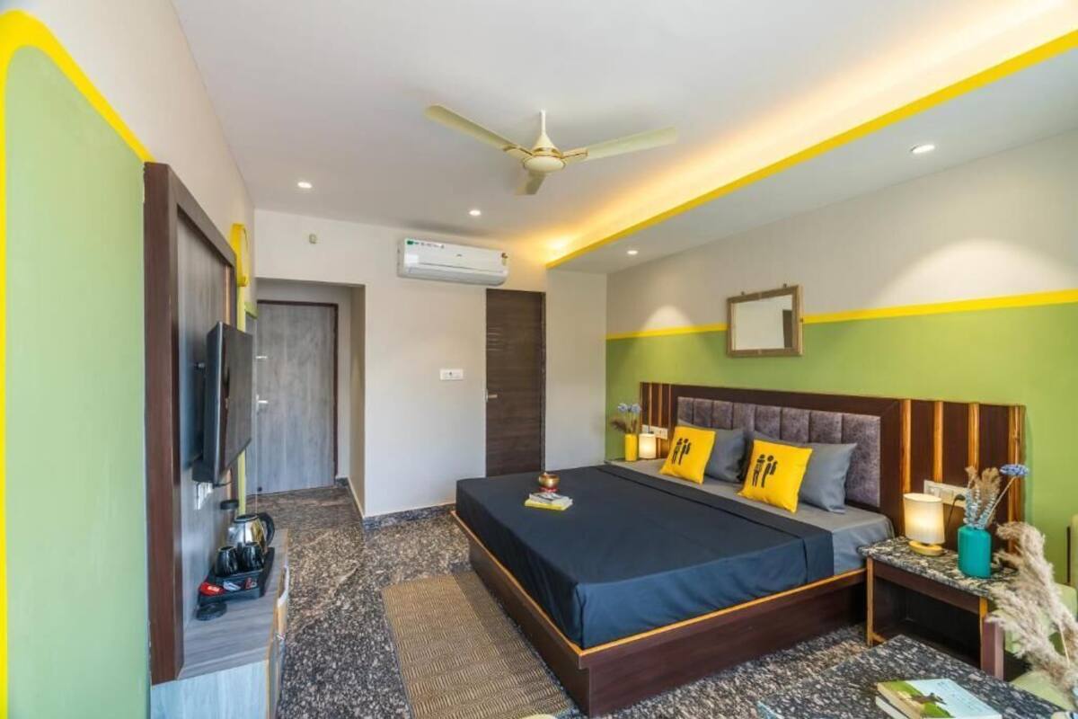 Une chambre à coucher moderne, équipée d’un lit, de tables de chevet, d’un ventilateur de plafond et d’un téléviseur.