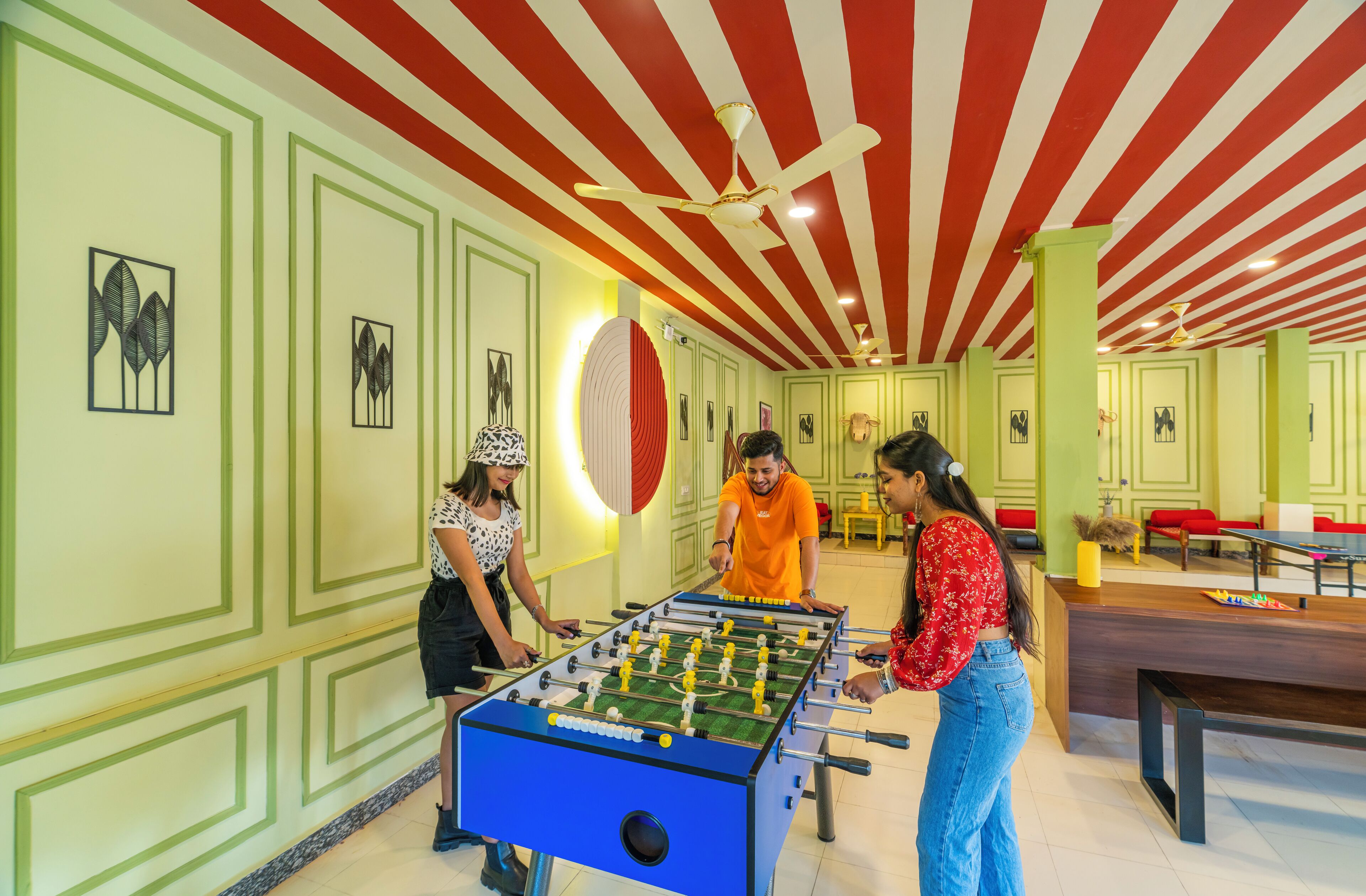 A room with a foosball table, green walls, and a red and white striped ceiling.