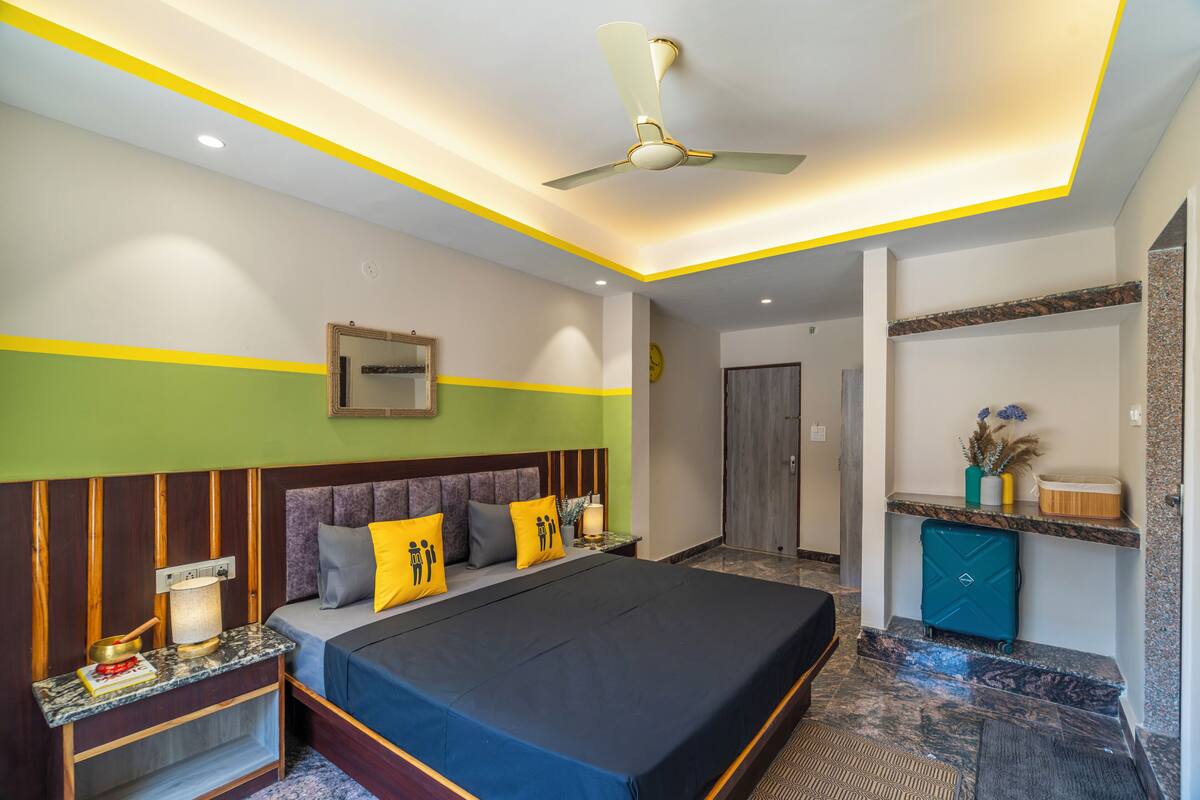 Une chambre d’hôtel avec un grand lit, une table de chevet, un bureau et un ventilateur de plafond.