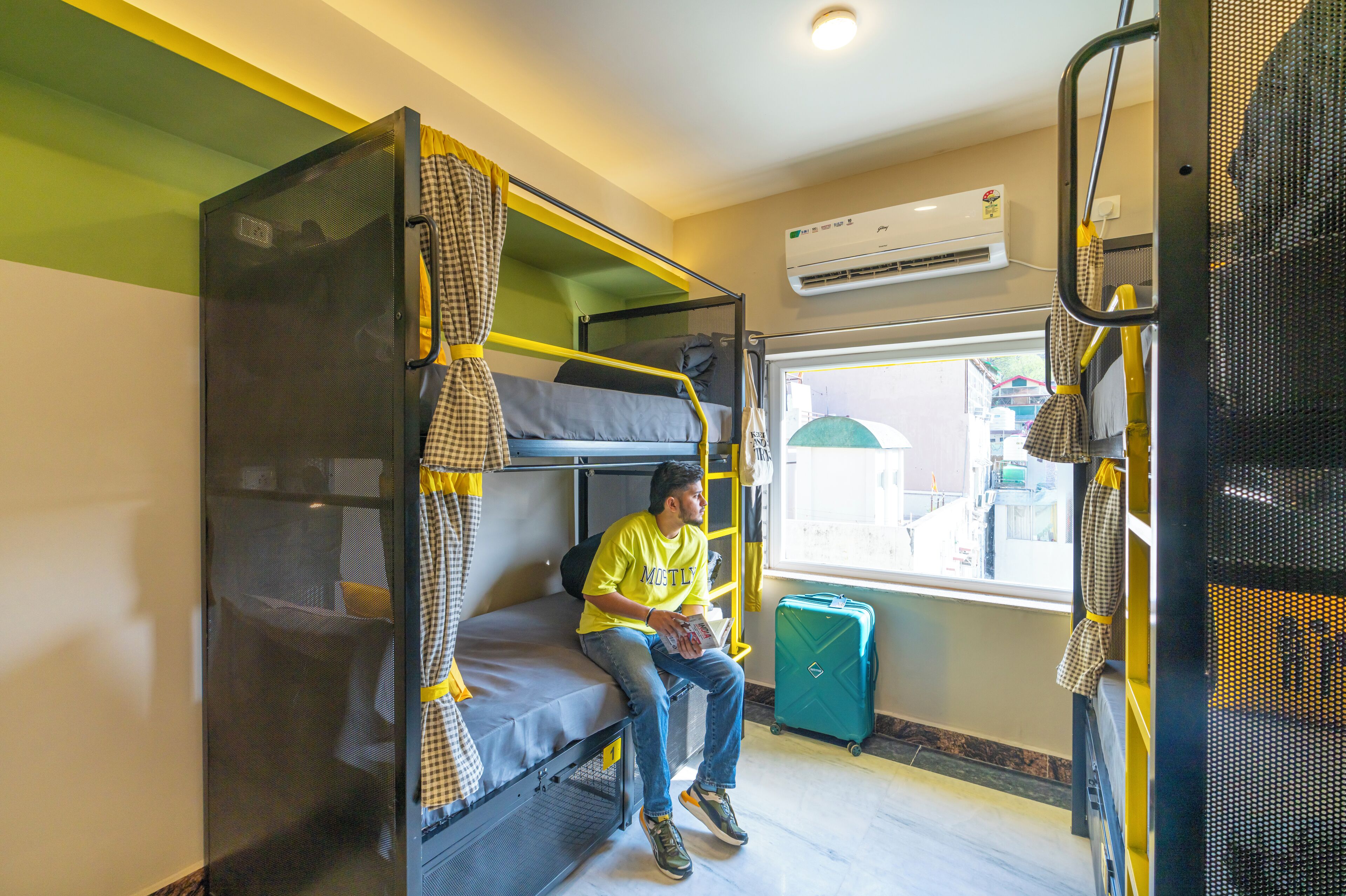 A bunk bed room with a window, a suitcase, and an air conditioning unit.