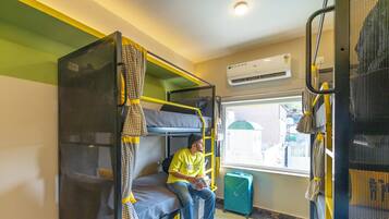 A bunk bed room with a window, a suitcase, and an air conditioning unit.