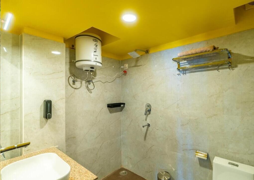 A bathroom with a white sink, a shower with a handheld showerhead, a towel rack, and a toilet.