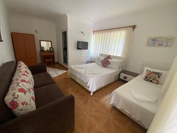 A hotel room with a bed, a sofa, a desk, and a wardrobe.