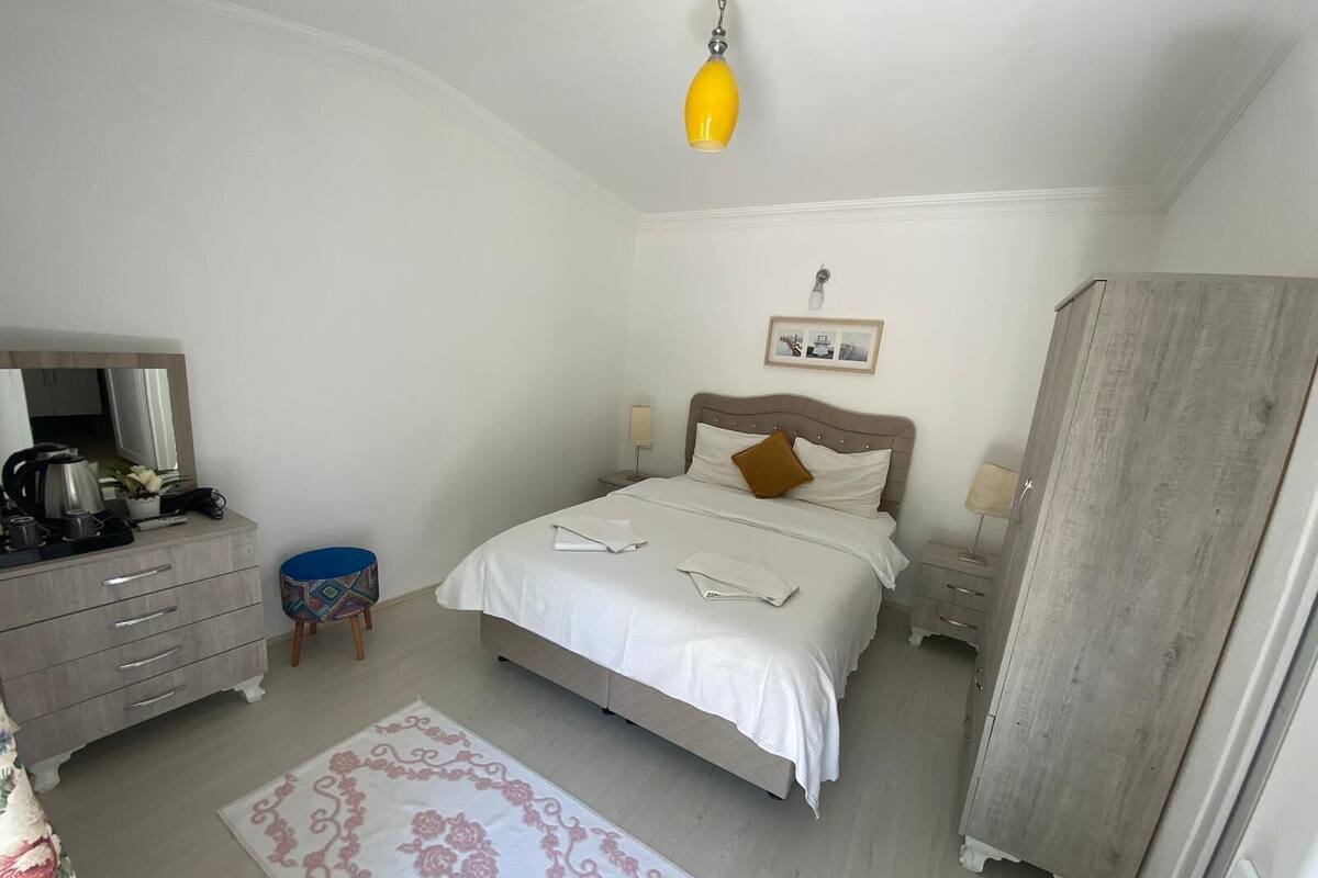 A bedroom with a bed, bedside tables, a dresser, a mirror, a lamp, and a wardrobe.