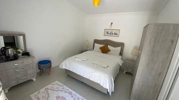 Ein Schlafzimmer mit Bett, Nachttischen, einem Schminktisch, einem Spiegel, einer Lampe und einem Kleiderschrank.