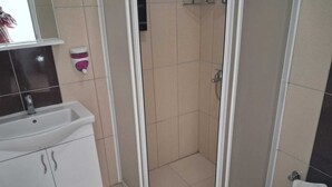 Et badeværelse med vask, toilet og bruser.