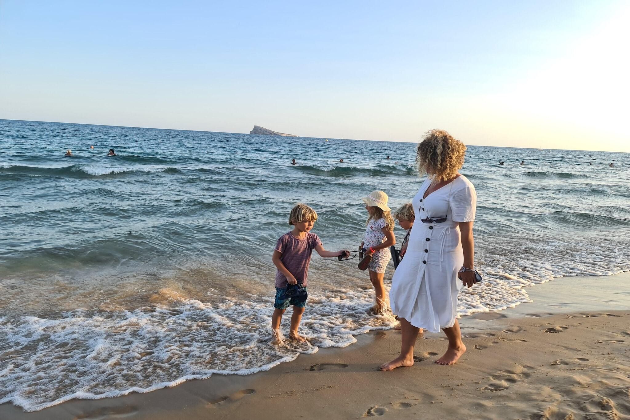 A beach scene with people near the water's edge.
