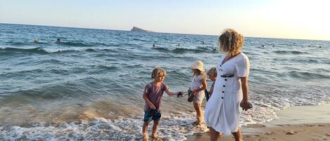 A beach scene with people near the water's edge.