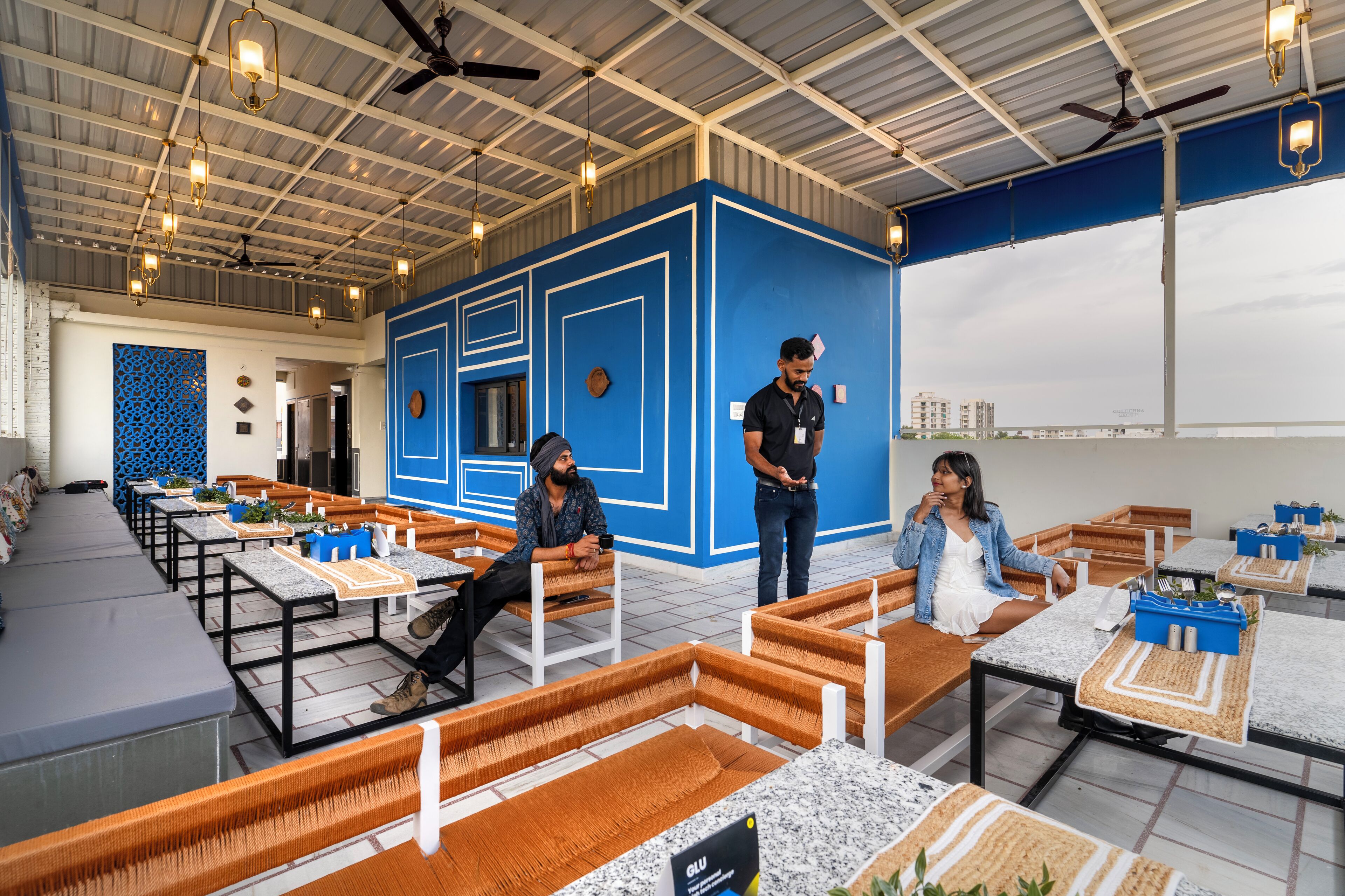 A modern indoor space with seating areas, a blue accent wall, and ceiling fans.