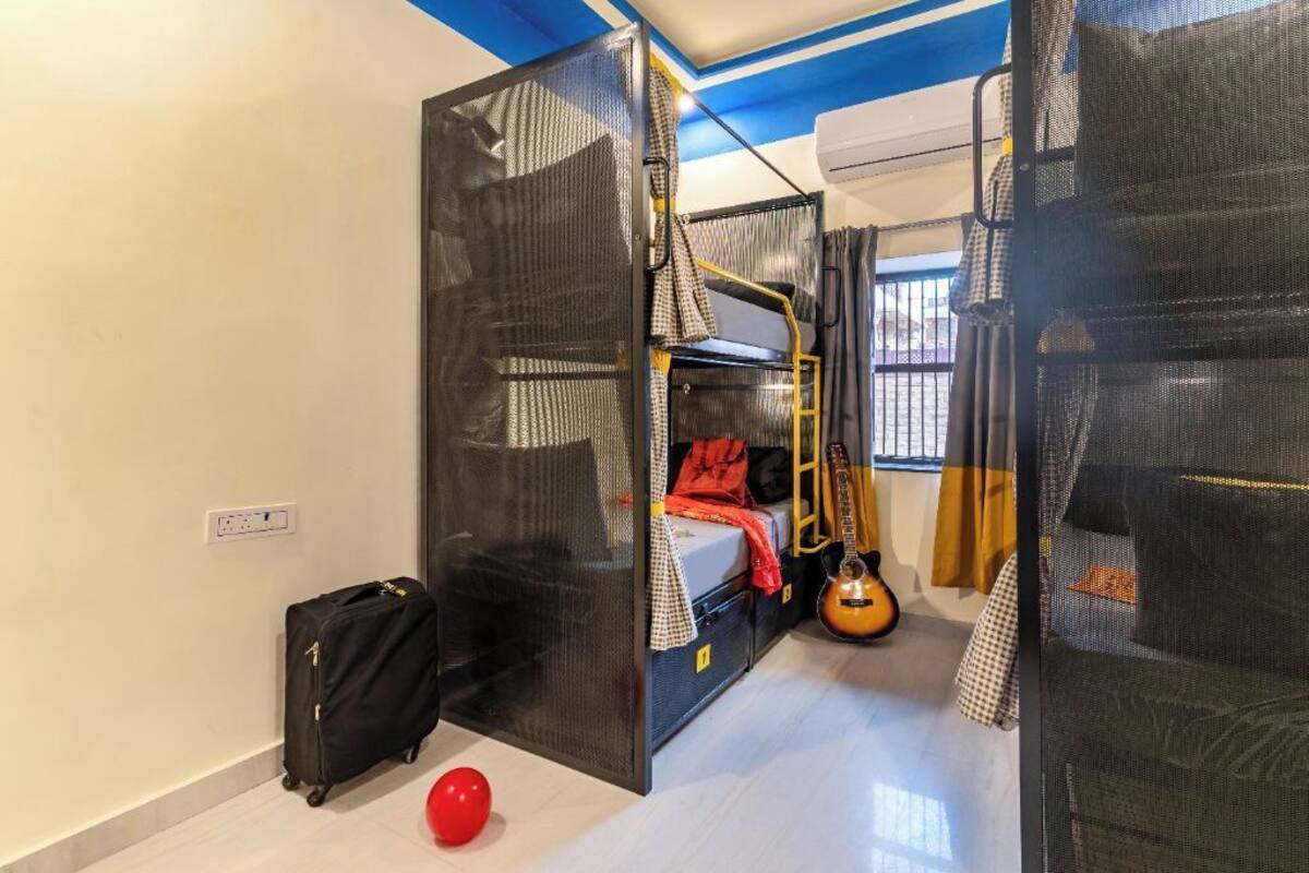 Une chambre avec des lits superposés, une guitare, une valise et un ballon rouge.