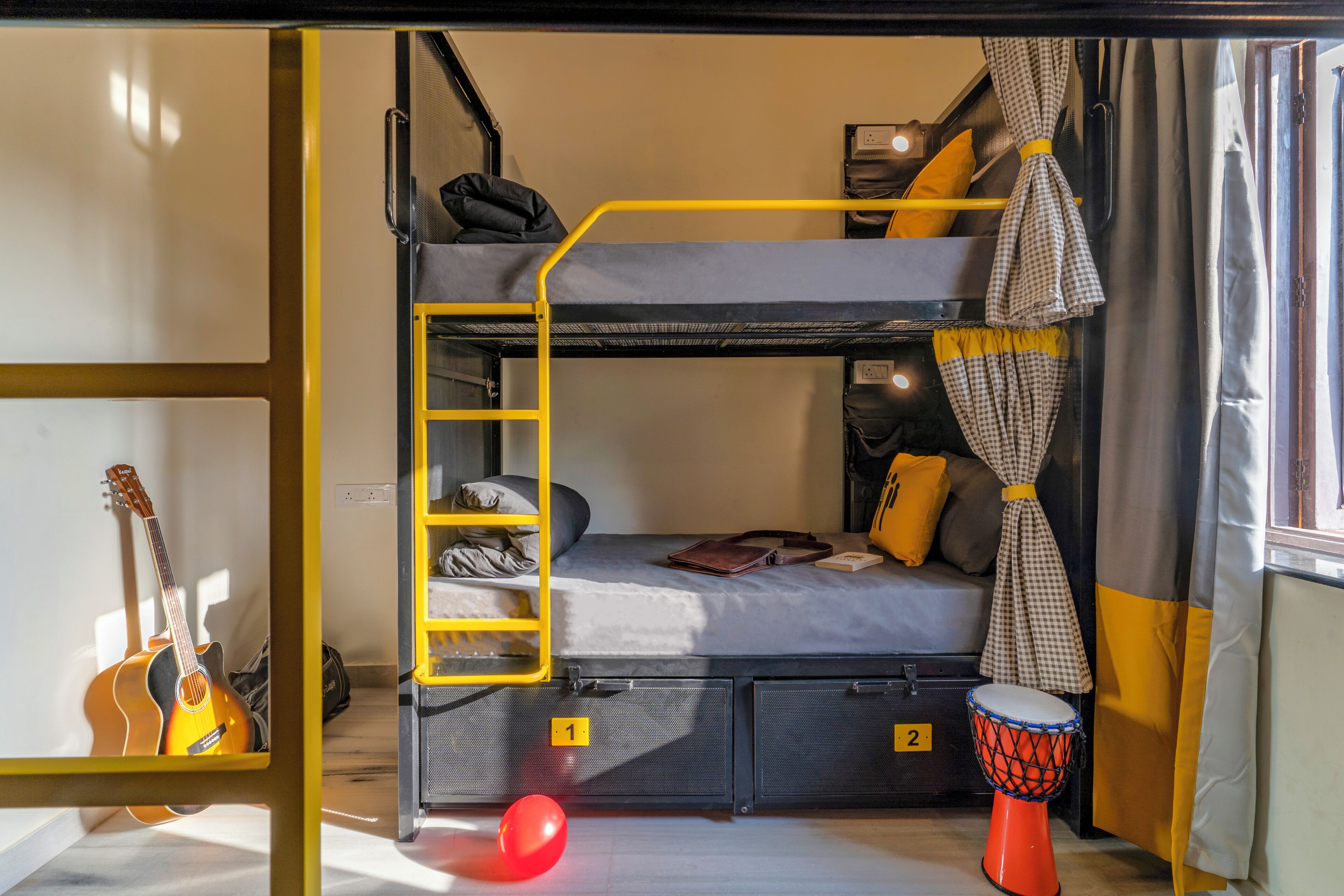 Una cama litera con escalera, una guitarra, un globo rojo y una batería.